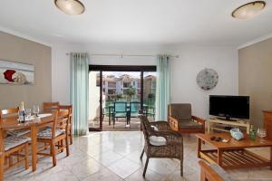 a living room with a table and chairs and a television at Columbus Beach Apartment in Quarteira