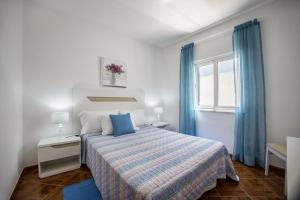 a bedroom with a bed and a window with blue curtains at Casa Fernandes in Burgau +40 photos
