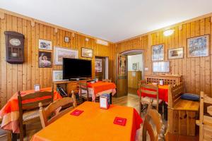 una sala da pranzo con tavoli e sedie e una televisione di Albergo Trieste - Lorenzago a Lorenzago