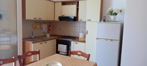 a small kitchen with a table and a white refrigerator at Villetta Lucy in Salve