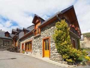 a stone house with a yellow door on a street at Appartement - Vue montagne in Cazeaux-de-Larboust