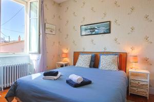 a bedroom with a bed with blue sheets and a window at Villa Rosella in Les Sables-d'Olonne