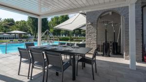 a dining table and chairs on a patio with a pool at Villa Sirmione Front Lake in Sirmione