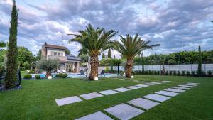 a yard with palm trees and a house at Villa Sirmione Front Lake in Sirmione