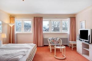 a bedroom with a bed and a tv and a chair at Ferienhaus Adler Bellevue in Hinterzarten