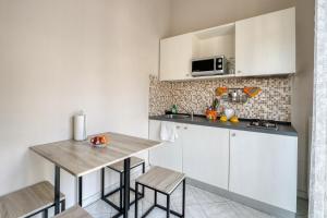 a kitchen with white cabinets and a table and chairs at Sant'Oronzo House in Lecce