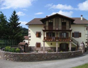 a large white house with a stone wall at Matxingonea 1 in Urdax