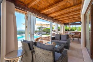 an outdoor living room with chairs and tables and a pool at Villa Flora Sea View in Cuile Pazzoni