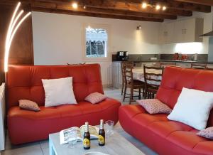 a living room with two red couches and a kitchen at Gîte Le Campet in Millau