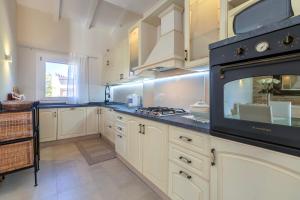a kitchen with white cabinets and a stove top oven at Villa Flora Sea View in Cuile Pazzoni