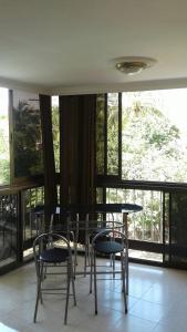 a group of chairs and tables in a room with windows at Apartamento buritaca 302 el rodadero in Santa Marta