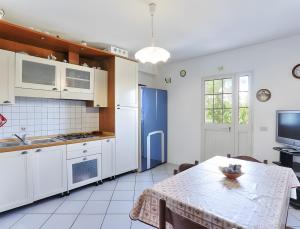 a kitchen with white cabinets and a table and a television at Appartamento Tramonto in Capoliveri
