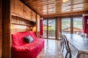 a living room with a red couch and a table at La Flèche d'Or in Châtel