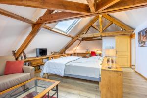 a large attic bedroom with a bed and a couch at Chambres D'hôtes Le Palmier in Sevremont
