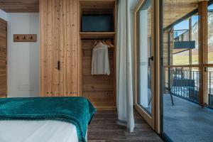 a bedroom with a bed and a sliding glass door at Arnica Alpin Lodge 1 in Cavedago