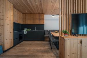 a kitchen with wooden walls and a table with a television at Arnica Alpin Lodge 1 in Cavedago