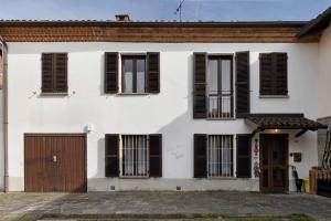 a white house with black shuttered windows at Casa Dello Zio Birba in Portacomaro