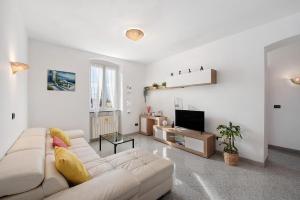 a white living room with a couch and a tv at Mela Garden House in Genoa