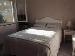 a bedroom with a bed with a white comforter and a window at Sweet Home - Gujan-Mestras in Gujan-Mestras