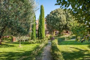 a path through a garden with trees and grass at La Ripa - Appartamento Il Fienile in San Gimignano