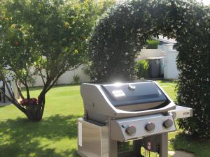 a grill sitting in a yard next to a tree at Sweet Home - Gujan-Mestras in Gujan-Mestras