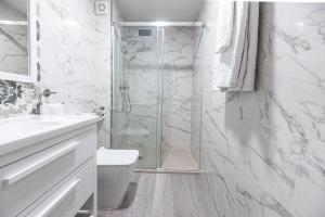 a white bathroom with a shower and a toilet at Ocean Suites A1 in Isla Cristina +14 photos