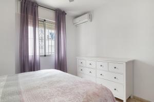 a bedroom with a bed and a dresser and a window at Casa En El Centro De Barbate in Barbate