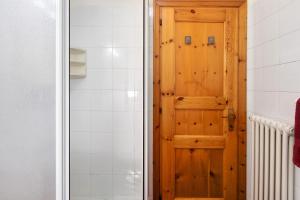 a bathroom with a wooden door next to a shower at Cima de' Piazzi Apartment 1 in Valdidentro +18 photos
