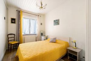 a bedroom with a yellow bed and a chair at Maison Pêcheur, jardin et plage -1 in Pornic