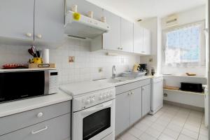a white kitchen with white appliances and a window at Maison Pêcheur, jardin et plage -1 in Pornic