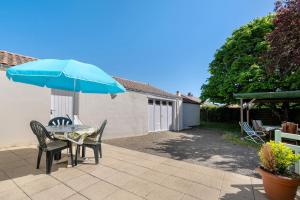 a table and chairs with a blue umbrella on a patio at Maison Pêcheur, jardin et plage -1 in Pornic
