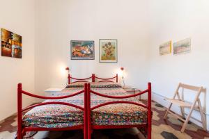 a bedroom with a red bed and a chair at Casa Damiano 1935 in Villasimius
