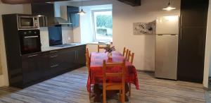 a kitchen with a table with chairs and a refrigerator at Gîte De La Verdurette in Pettonville