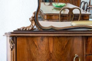 a mirror on top of a wooden cabinet with a table at Casa Damiano 1935 in Villasimius