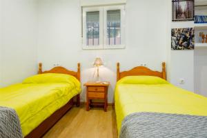 two beds in a room with yellow sheets and a lamp at Casa Familiar con Piscina in La Rinconada +19 photos