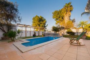 a swimming pool in a yard with a chair next to at Casa Familiar con Piscina in La Rinconada
