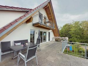 a patio with a table and chairs and a balcony at Waldsuite in Friedrichshafen