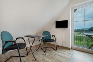 a room with two chairs and a table and a tv at Waldsuite in Friedrichshafen