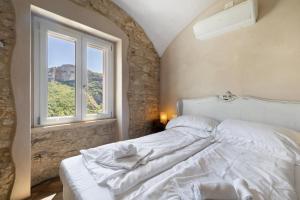 a bedroom with a white bed with a window at Casa Virginia - Vigna in Orco Feglino +20 photos