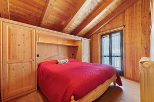 a bedroom with a red bed in a wooden room at La Maison de Marguerite in Saint Vincent