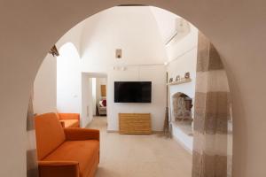 an archway leads into a living room with an orange couch at Trulli Aletheia Con Piscina Privata in Ceglie Messapica