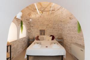 a bedroom with a bed in a stone wall at Trulli Aletheia Con Piscina Privata in Ceglie Messapica
