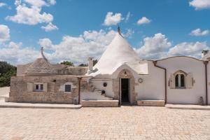 a church with a white building with a roof at Trulli Aletheia Con Piscina Privata in Ceglie Messapica