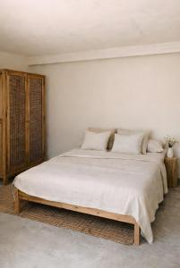 a white bedroom with a large bed with white sheets at Sa caseta mallorca Studio in Algaida