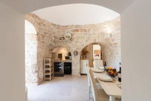 a kitchen with a table and a stone wall at Trulli Aletheia Con Piscina Privata in Ceglie Messapica