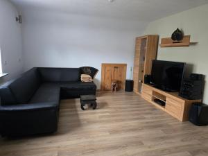 a living room with a black couch and a tv at Ferienwohnung Rimbach in Rimbach