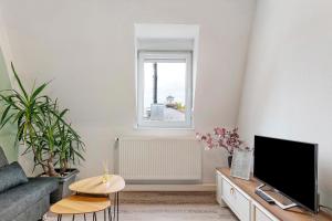 a living room with a tv and a couch and a window at Az-Living Feudenheim in Mannheim