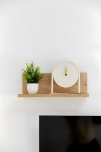 a clock on a wooden shelf with a plant at Casa Pablo City Center in Fuengirola