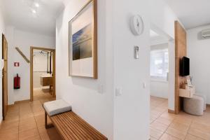 a living room with a bench and a clock on the wall at Almadrava House in Tavira