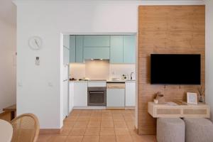 a kitchen with a flat screen tv on a wall at Almadrava House in Tavira